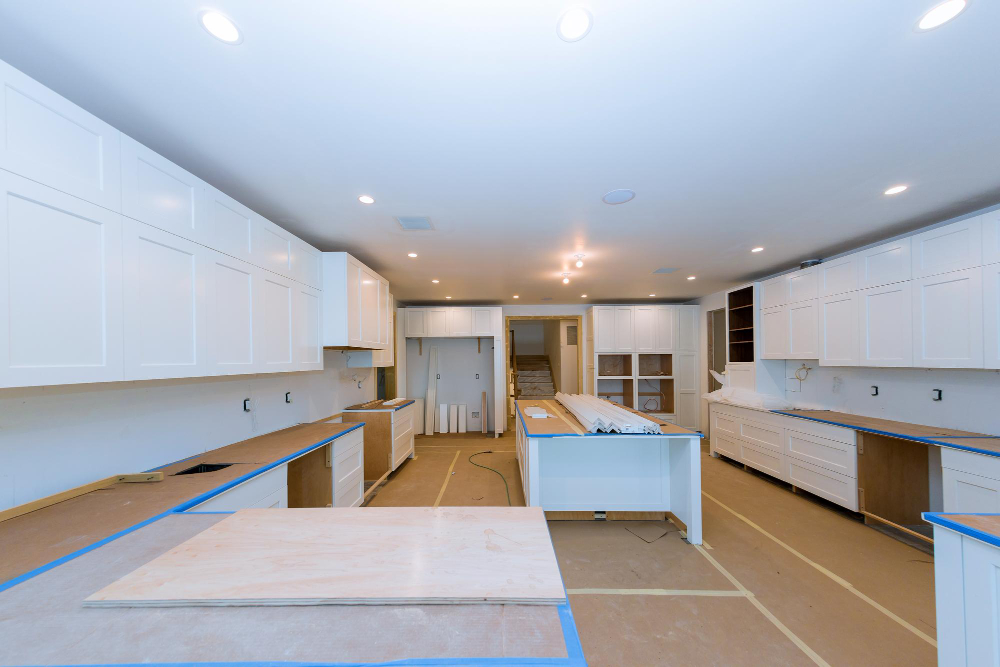 Basement kitchen renovation with white cabinets and island under construction