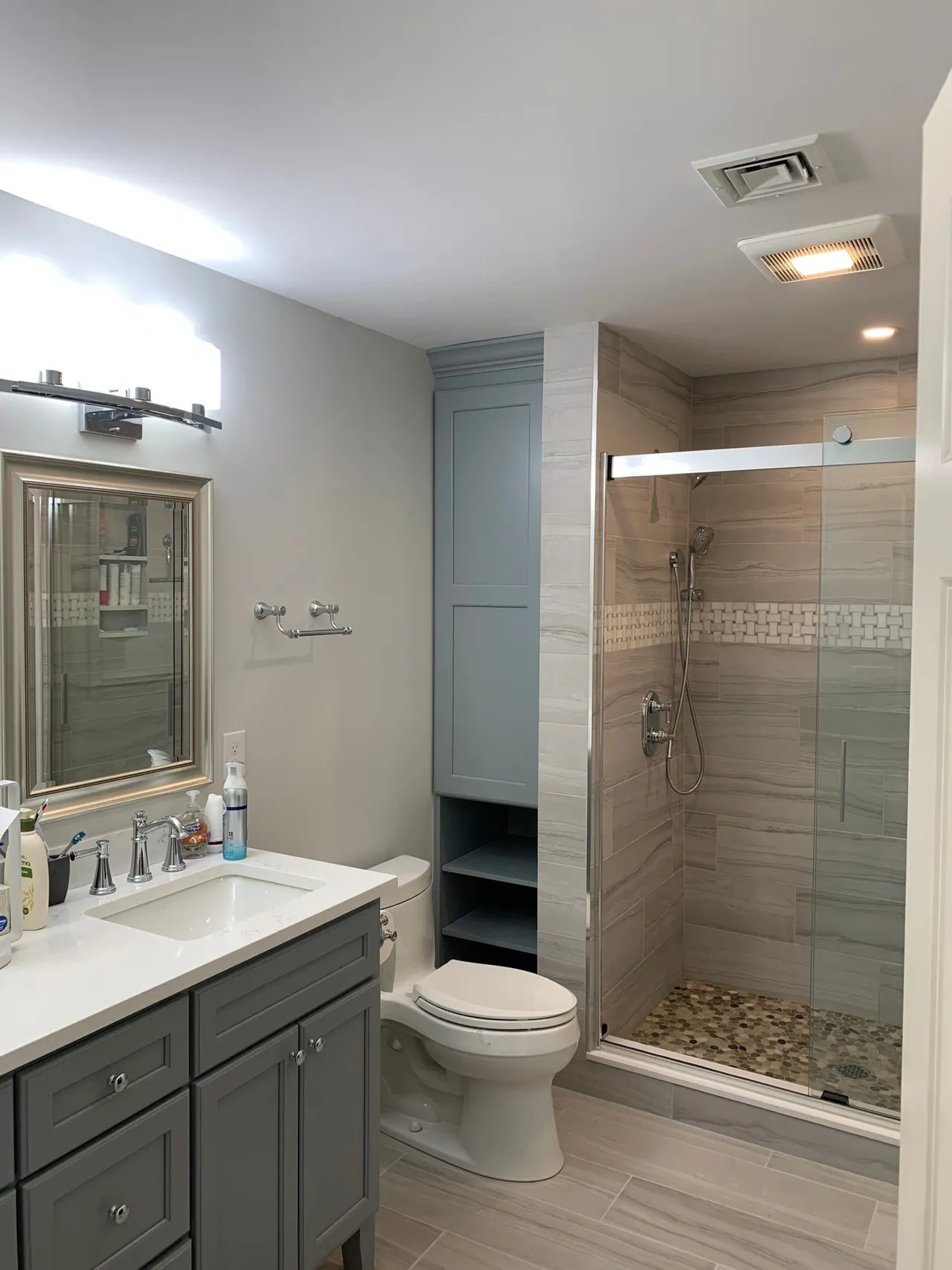 Bathroom remodel with gray vanity, walk-in shower, and built-in storage