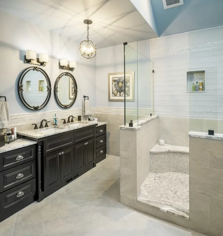 Luxury bathroom with double vanity, oval mirrors, and glass shower