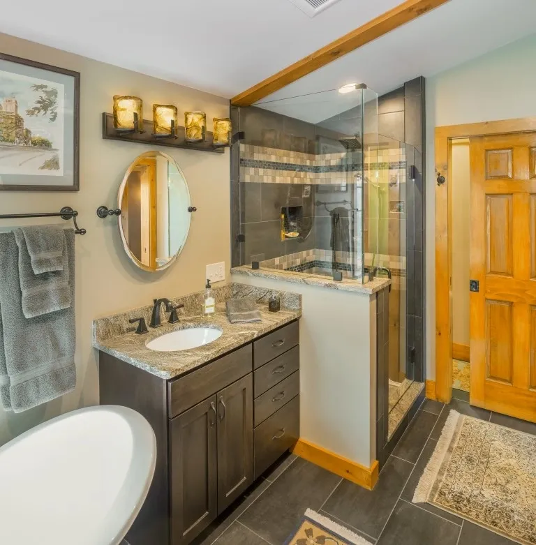 Bathroom featuring granite countertop, dark cabinets, and freestanding tub