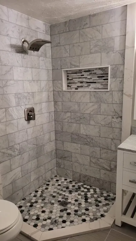 Marble tile shower with decorative niche and mosaic floor
