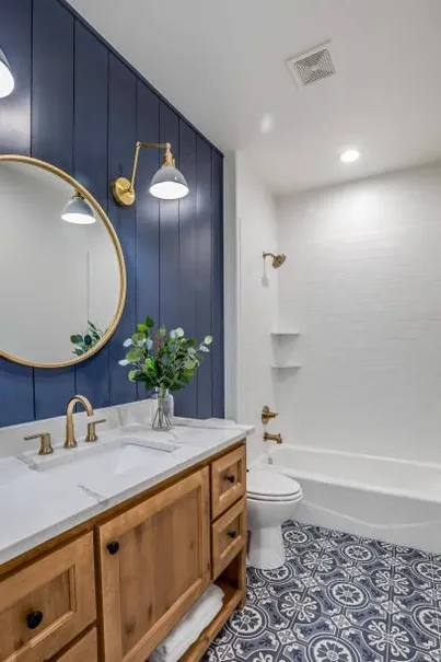 Bathroom with blue accent wall, wood vanity, and patterned floor tile