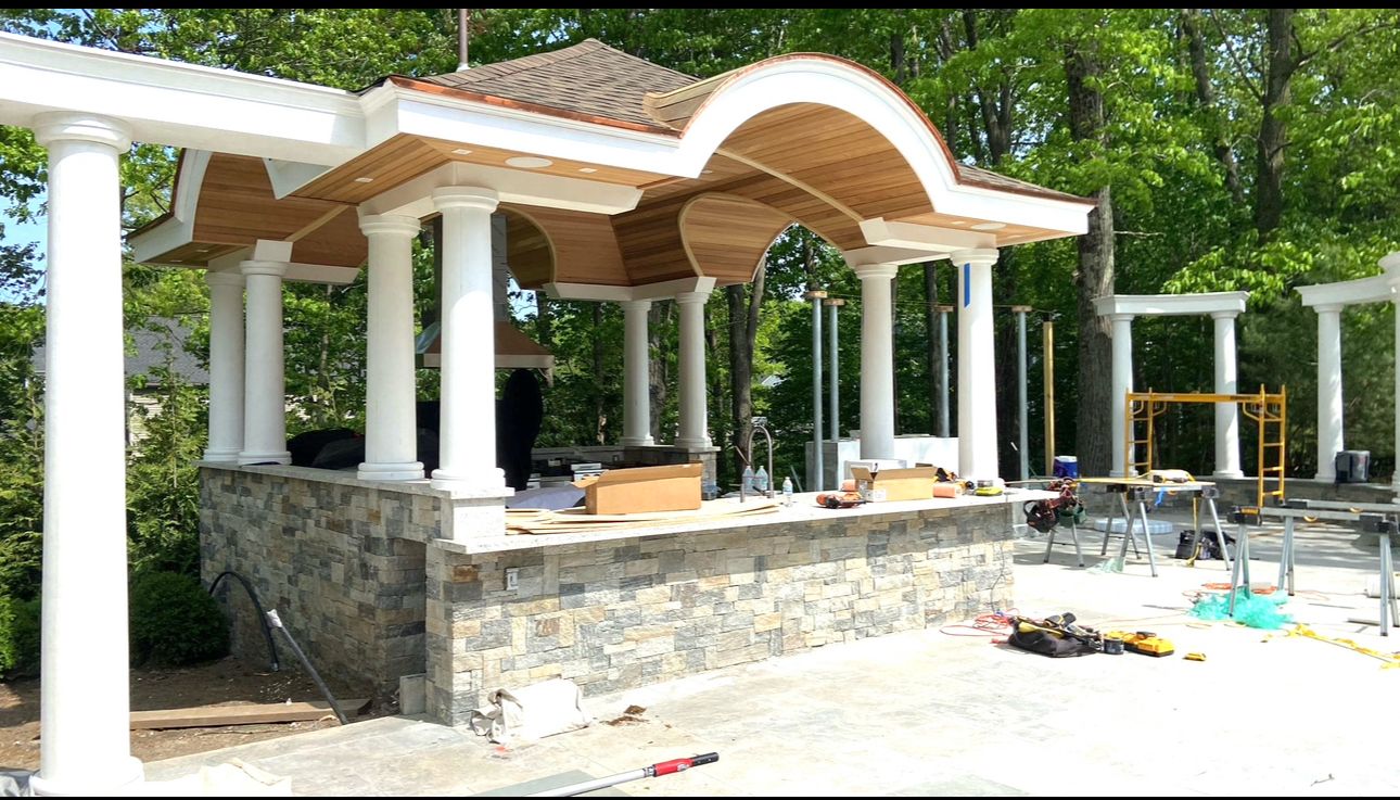 Luxury outdoor kitchen with arched pavilion and white columns in progress