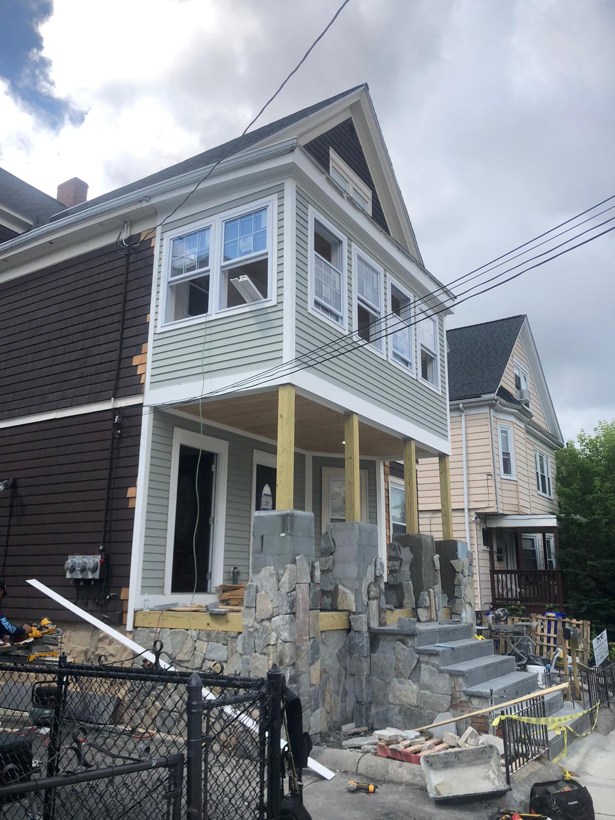 House exterior renovation in progress with stone foundation work