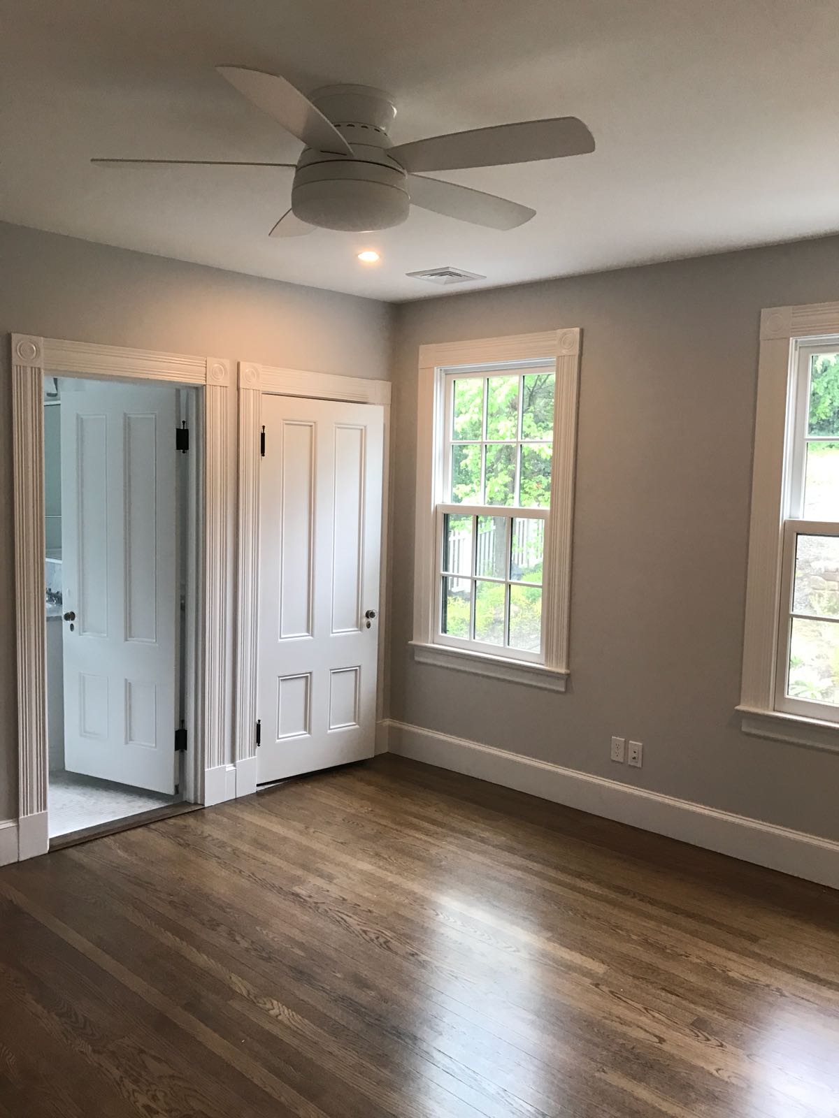 Beautiful hardwood flooring installation in bedroom with gray walls and ceiling fan