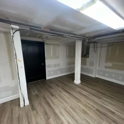 Modern basement with gray luxury vinyl plank flooring and structural columns