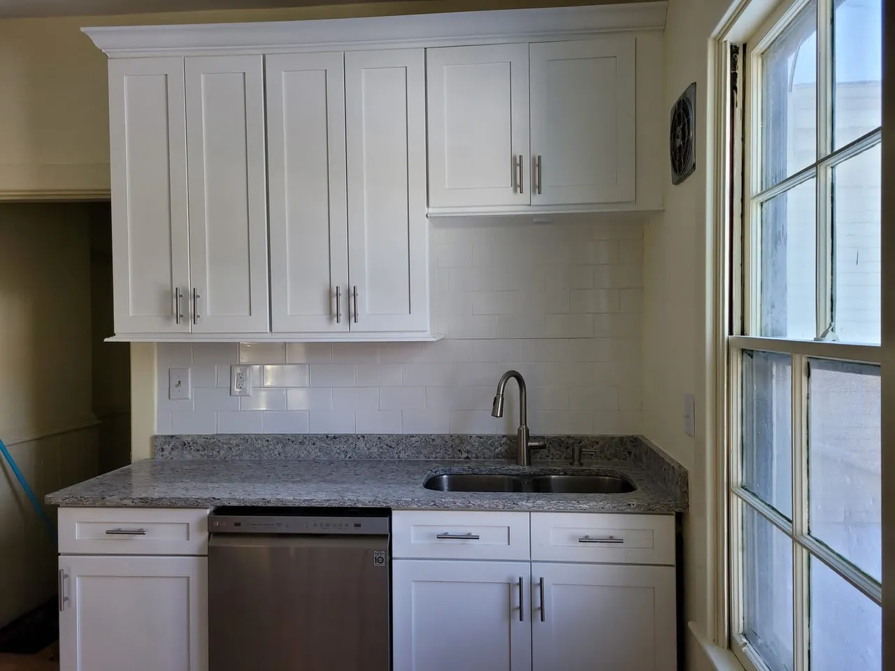 Modern white kitchen with gray granite countertops and subway tile backsplash