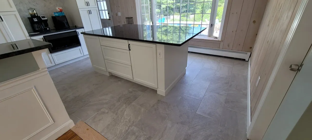 Modern kitchen with black island countertop and large format gray tile flooring