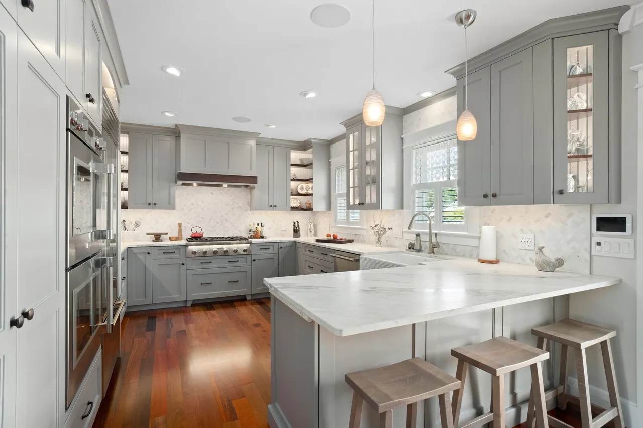 Sophisticated gray kitchen with white marble countertops and glass-front cabinets