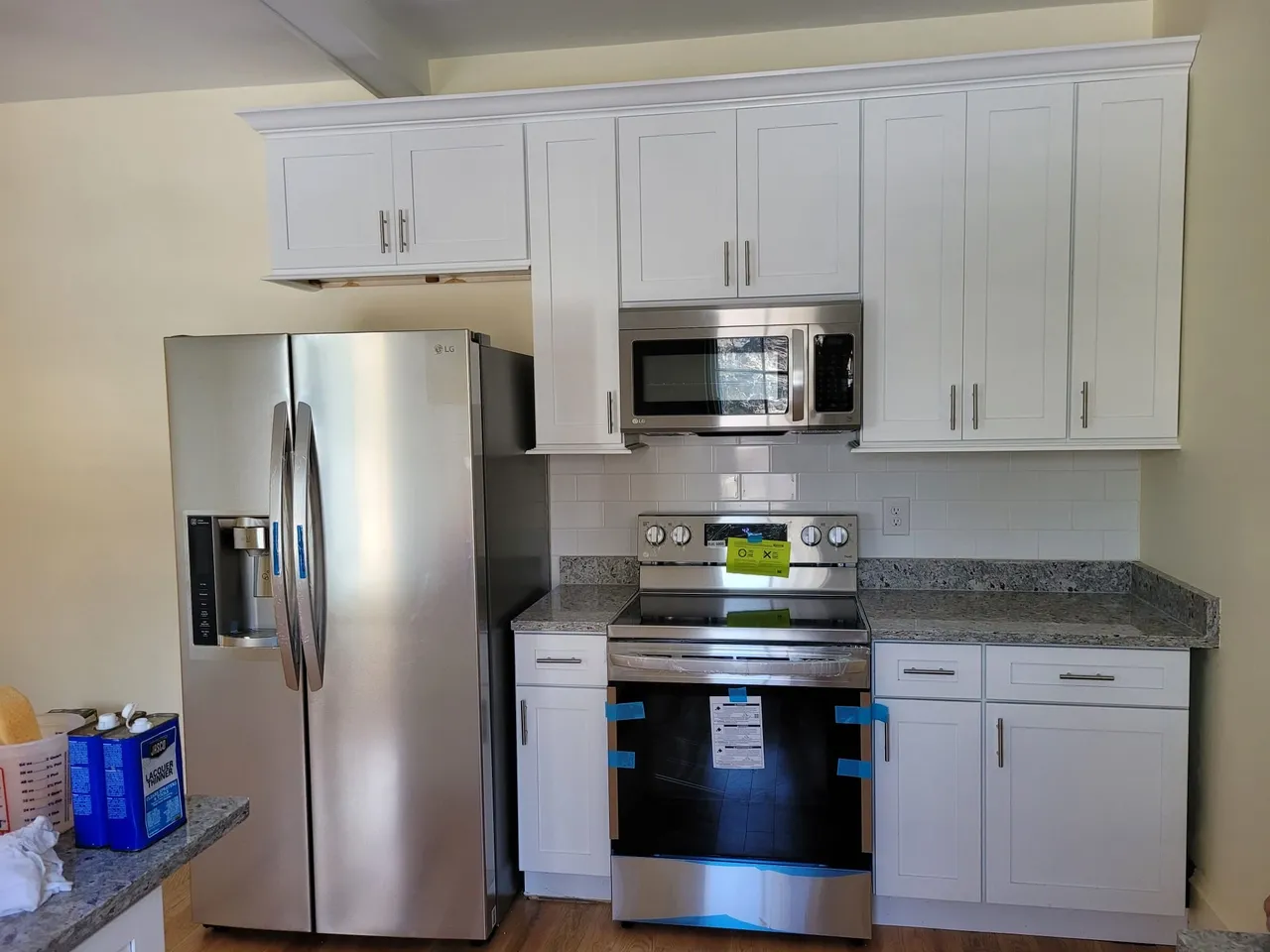 Bright white kitchen with gray granite, subway tile, and stainless steel appliances