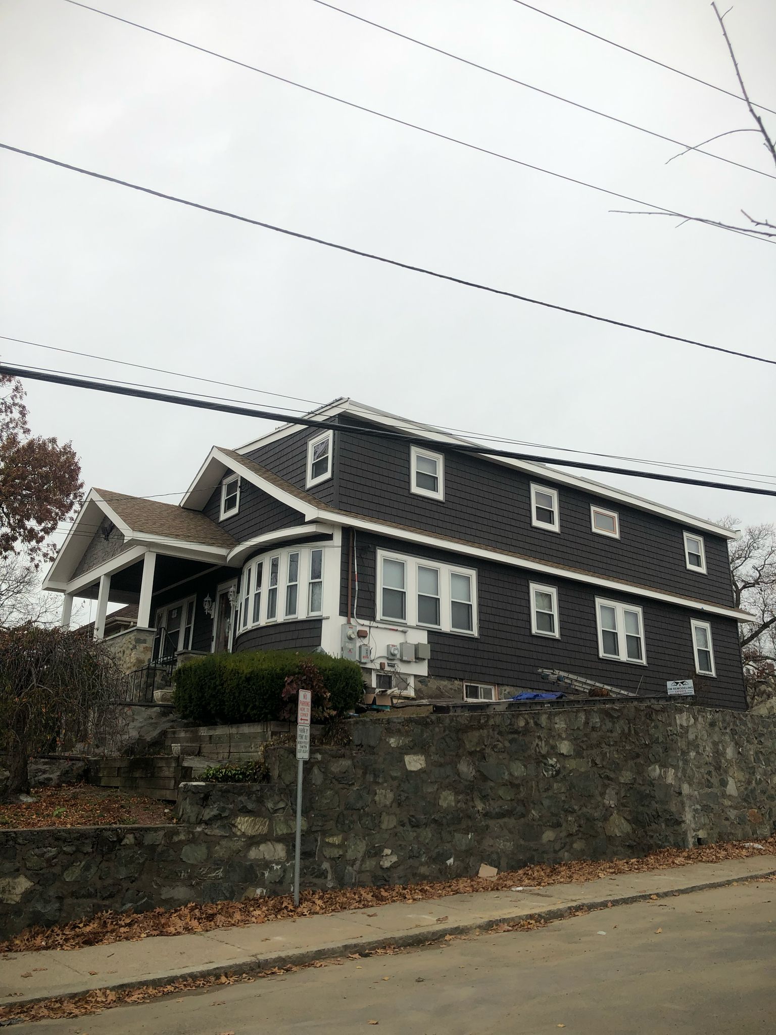 Charcoal gray house with white trim and stone retaining wall completed renovation