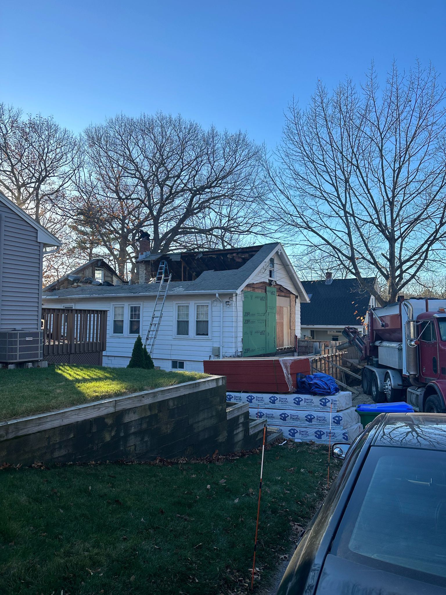 White house with roofing renovation in progress showing materials and equipment
