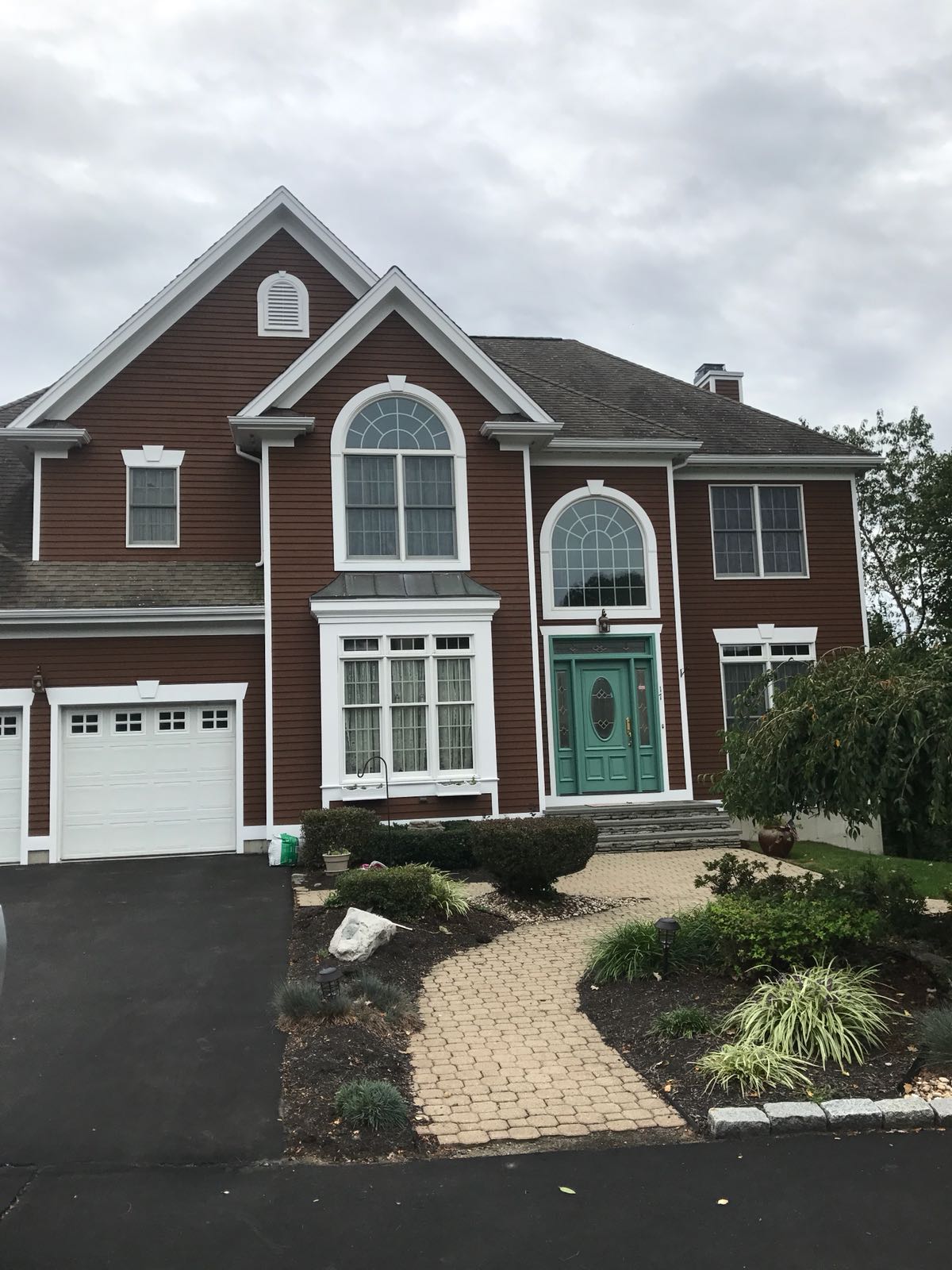 Two-story brown house with new dark shingle roof, white trim, and turquoise front door